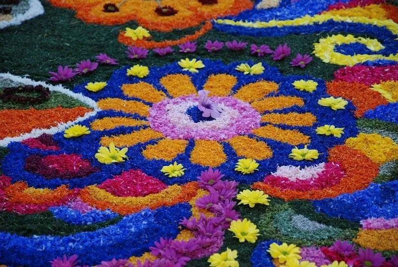 Dettaglio di un tappeto floreale delle Infiorate di Spello, con un grande fiore stilizzato composto da petali blu, arancioni, rosa e gialli