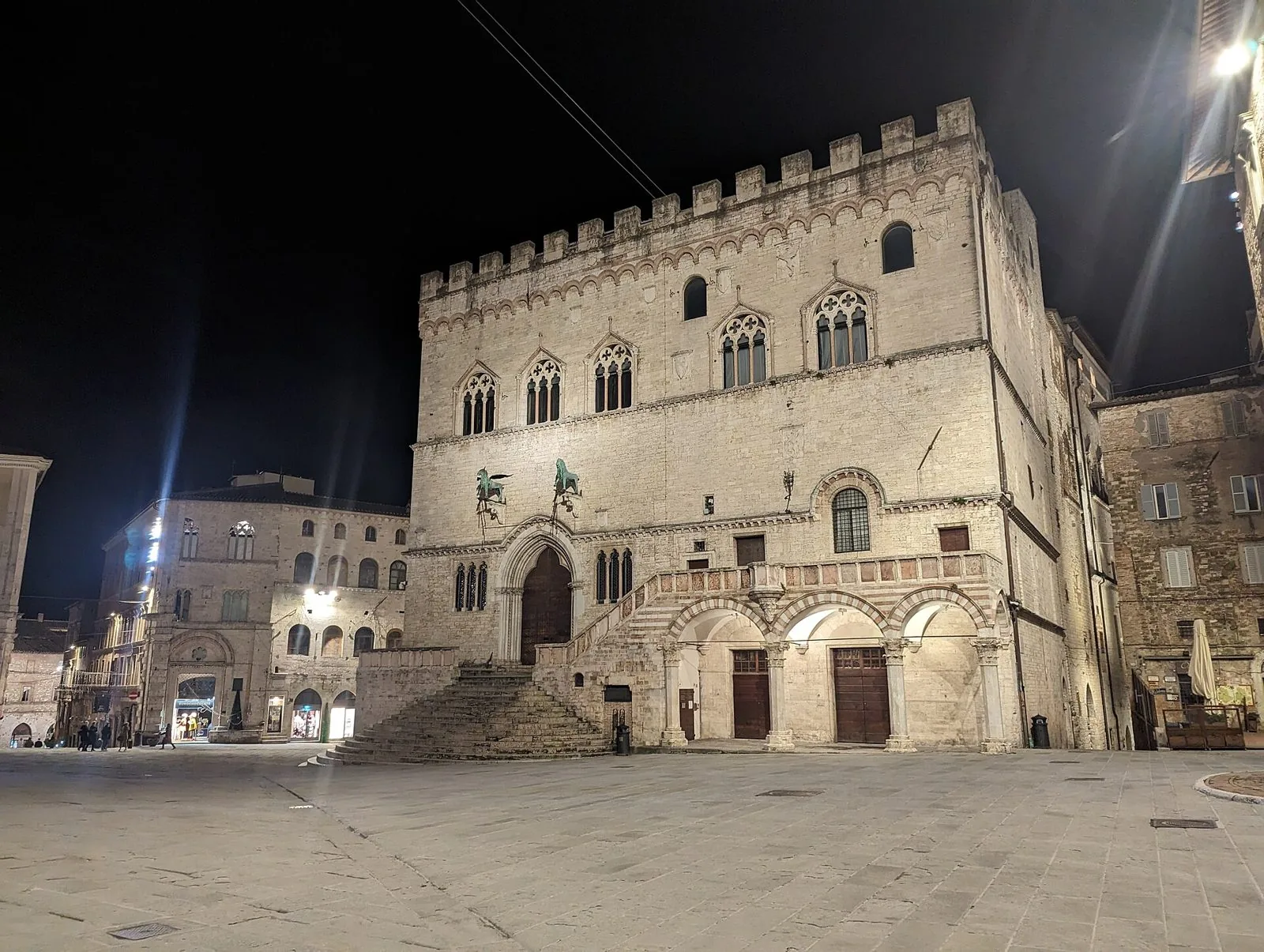 Il Palazzo dei Priori illuminato di notte affacciato su piazza IV Novembre a Perugia, con la grande scalinata e il loggiato ad archi